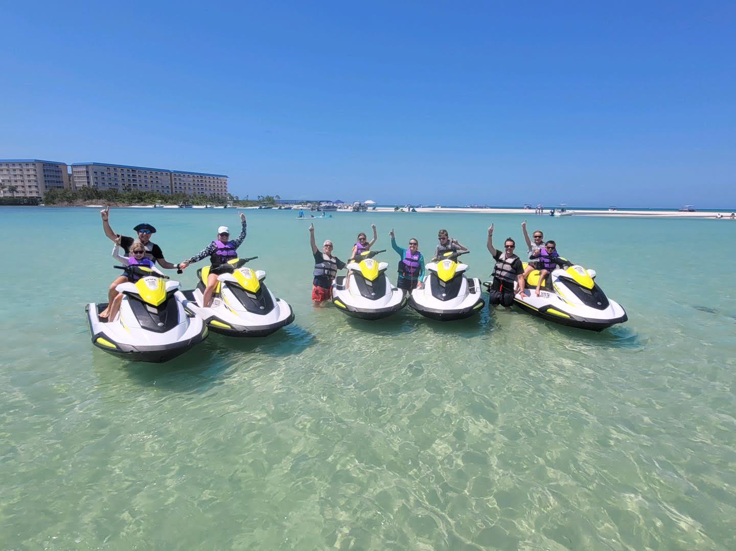 A group enjoying yellow and white WaveRunners in clear coastal water