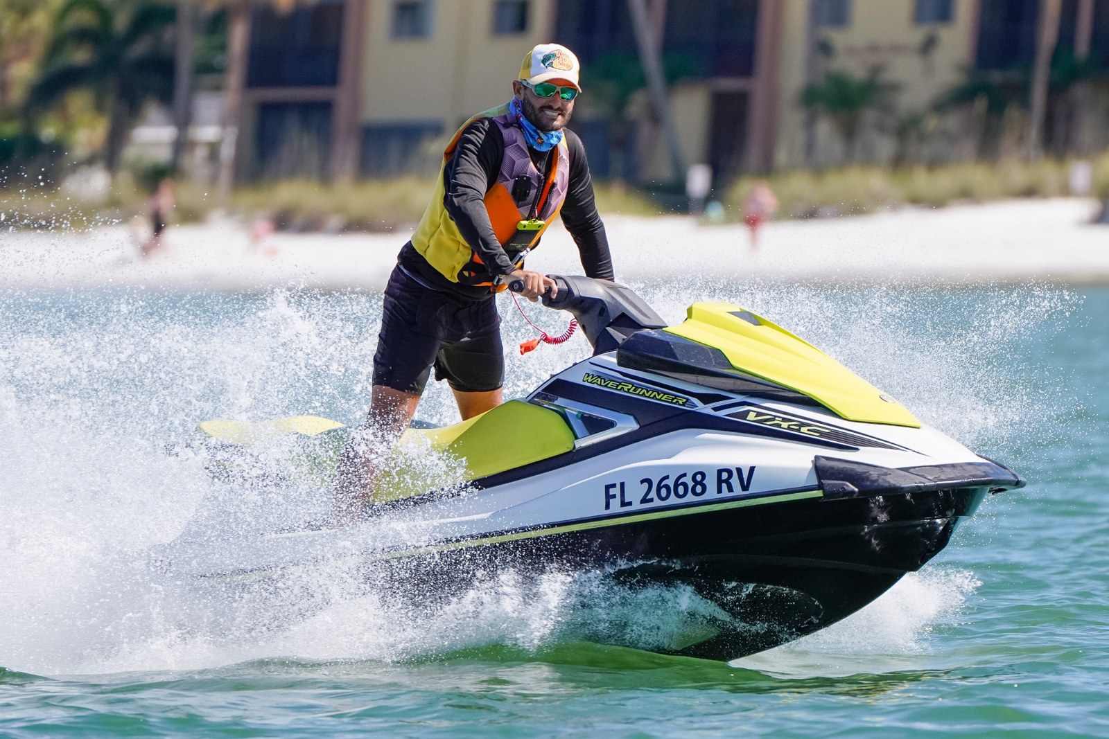 A rider wearing a life jacket enjoying a Yamaha WaveRunner with water spraying beside the Fort Myers Beach shoreline